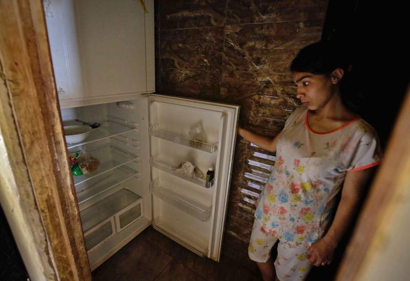 A Lebanese woman stands next to her empty refrigerator in her apartment in the port city of Tripoli. AFP