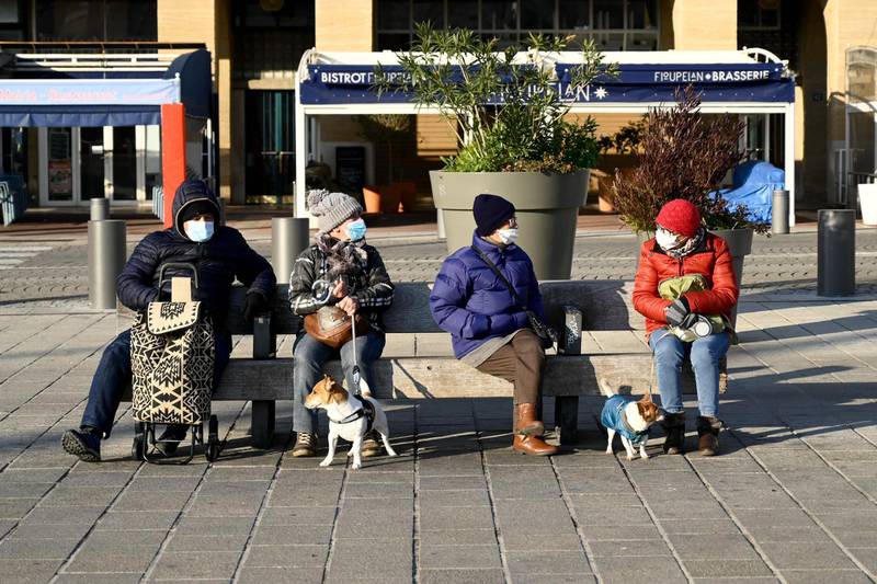 People wearing face masks sit on a bench in Marseille, southern France. AFP