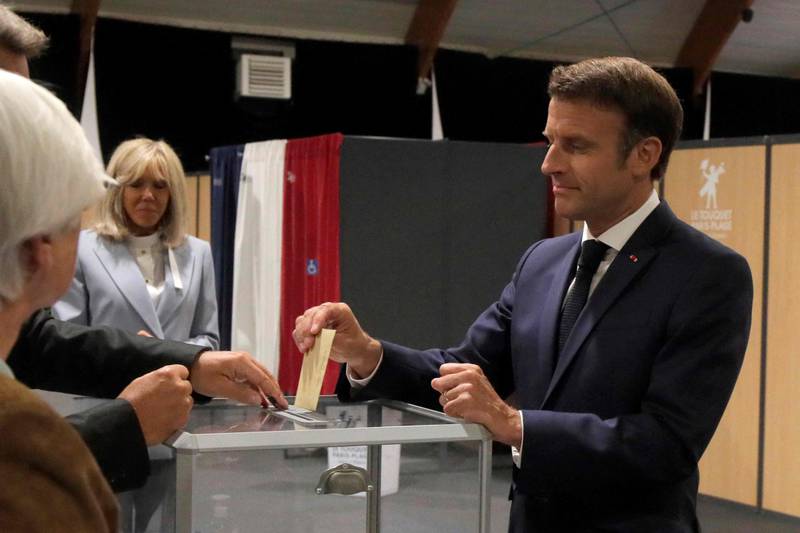 France's President Emmanuel Macron casts his ballot next to his wife Brigitte Macron during the second stage of French parliamentary elections at a polling station in Le Touquet, northern France on June 19, 2022. AFP