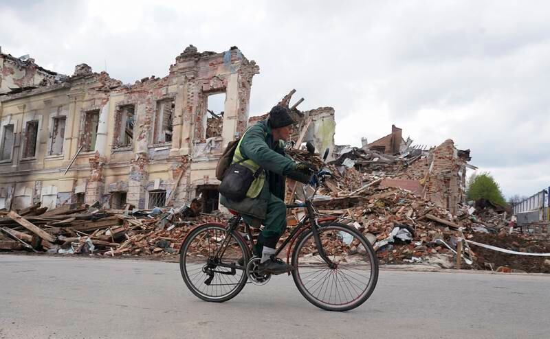 A Ukrainian man rides in front of a destroyed building in Kharkiv which had been shelled by the Russians. EPA