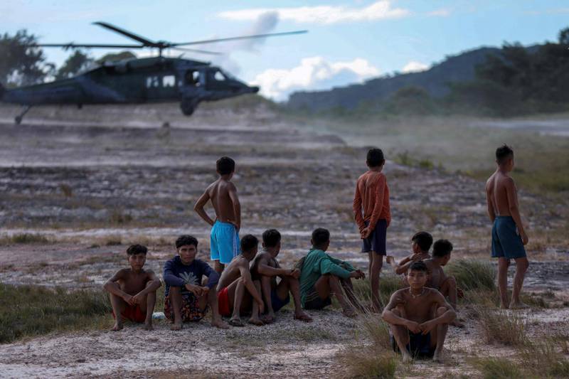 Yanomami indigenous men watch Brazil Air Force planes at the Surucucu airfield in Roraima, Brazil. AFP