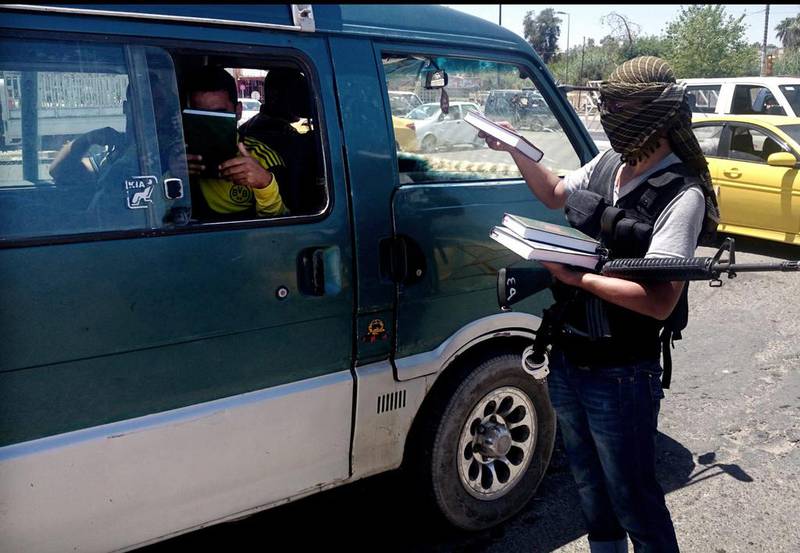 June 22, 2014: An ISIL fighter distributing a copy of the Quran to a driver in central Mosul. AP Photo