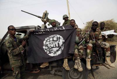 FILE PHOTO: Nigerian soldiers hold up a Boko Haram flag that they had seized in the recently retaken town of Damasak, Nigeria, March 18, 2015. REUTERS/Emmanuel Braun/File Photo