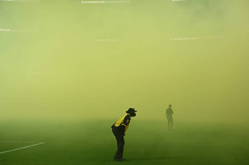 A security guard looks through the smoke at the start of a friendly football match between Los Angeles FC and Mexico's Club America at SoFi Stadium in Inglewood, California. AFP