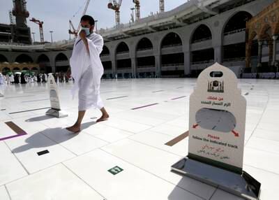 A Muslim pilgrim walks past a sign reminding Hajj participants of social distancing.