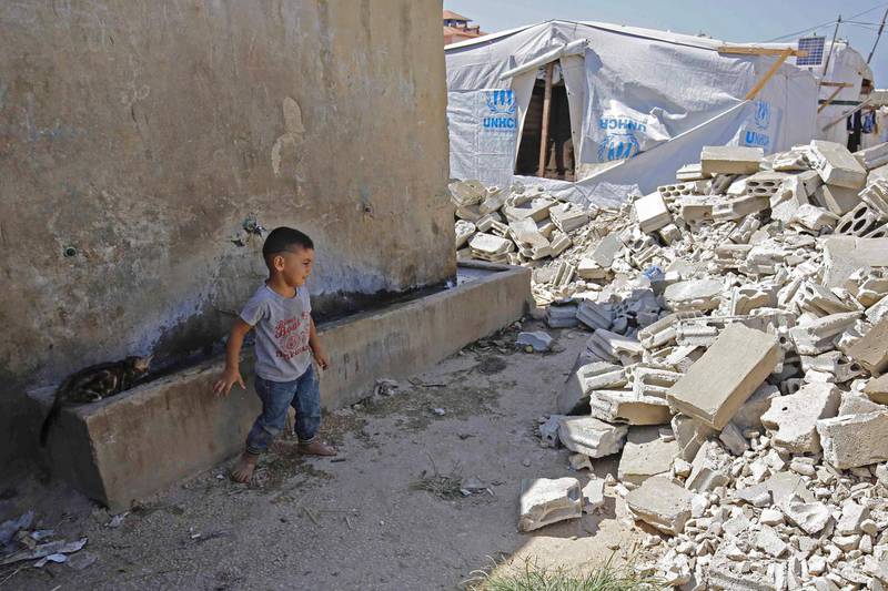 TOPSHOT - A Syrian child looks at the rubble of demolished concrete walls at a make-shift camp in the town of Rihaniyye in Lebanon's Akkar governorate on August 9, 2019. A coalition of international NGOs said the Lebanese army raided Syrian refugee settlements destroying a number of tents, urging authorities to stop the demolitions. Troops raided more than 30 settlements in the northern Akkar region today and at least five more tomorrow. / AFP / Ibrahim CHALHOUB
