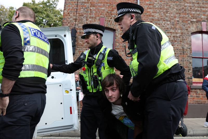 Police officers remove a man arrested for throwing an egg at King Charles III during his visit to York. Reuters