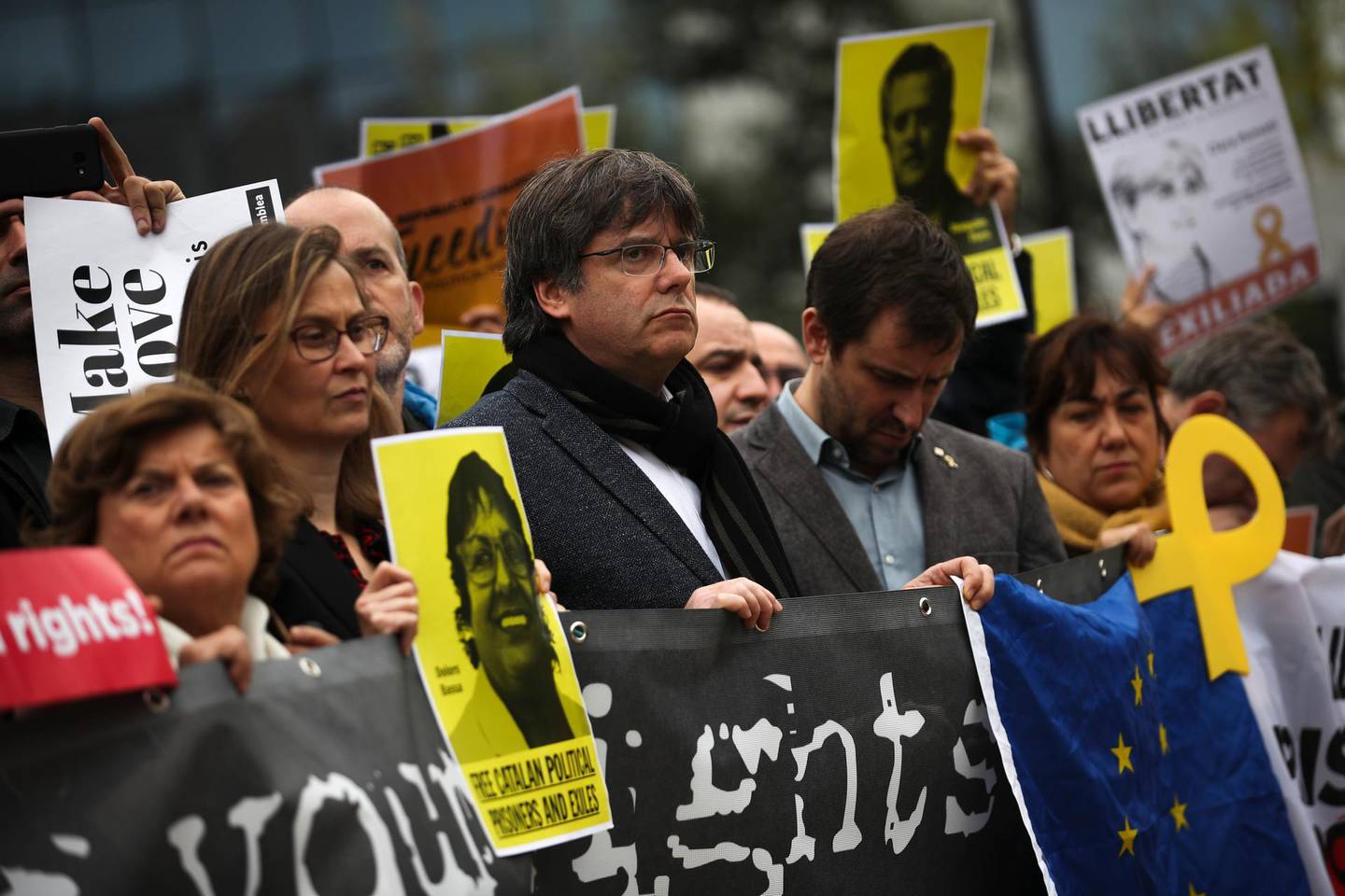 Catalonia's former regional president Carles Puigdemont, center, holds a banner with others during a protest in front of the European Commission headquarters in Brussels, Tuesday, Oct. 15, 2019. New disruptions to Catalonia's transportation network on Tuesday followed a night of clashes between activists and police over the conviction of separatist leaders, as Spanish authorities announced an investigation into the group organizing the protests. (AP Photo/Francisco Seco)