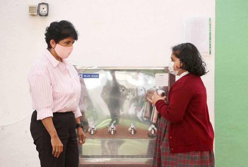 Asha Alexander, Gems Legacy School principal, with a pupil who is refilling her bottle from a water fountain at the campus.