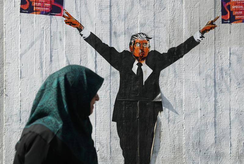 A Muslim woman walking past a street artist's rendition of US president Donald Trump on June 27, 2017 in Berlin, Germany. The US supreme court recently partially lifted a blockade by lower courts of Mr Trump's travel ban on people from six predominantly Muslim countries, though the court decision allows people with a viable connection to the US. Sean Gallup / Getty Images