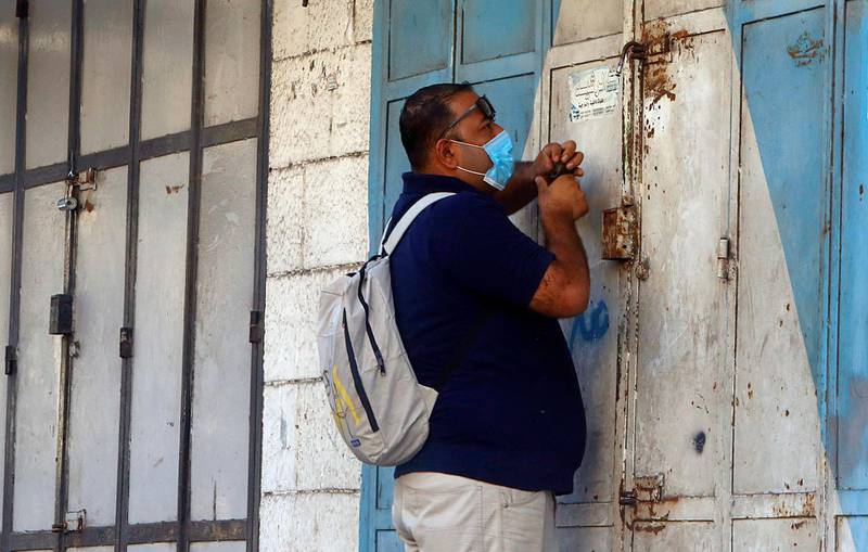 A Palestinian man wears a face mask as he locks a shop during a 48-hour lockdown. AP