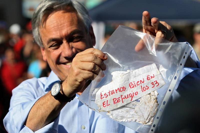 Chilean President Sebastian Pinera shows a message reading "We are fine in the refuge, the 33 of us", from the miners trapped in the San Esteban gold and copper mine, near the city of Copiapo, Atacama desert, 800 km (480 miles) north of Santiago, on August 22, 2010. The miners are alive and contact has been established with them 17 days after a structural collapse trapped them below ground.  AFP PHOTO/ HECTOR RETAMAL (Photo by HECTOR RETAMAL / AFP)