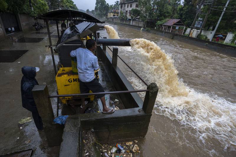 Workers use a pump to remove water from a flooded road in Guwahati. AP 