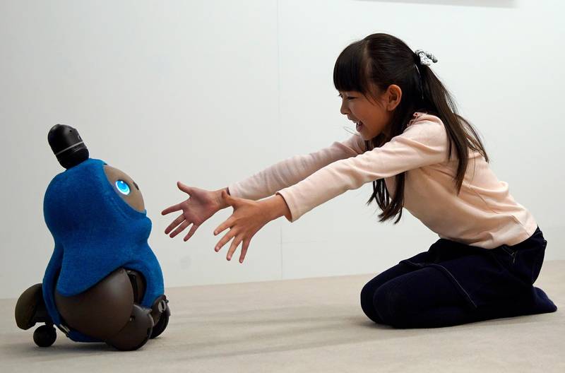 A young girl reaches out to GROOVE X's new home robot 'LOVOT' during its presentation at a press event in Tokyo, Japan. EPA