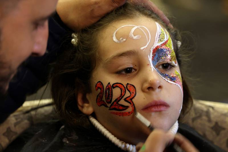 An artist paints 2023 on the face of a Palestinian girl ahead of New Year's celebrations, in Gaza City. AFP
