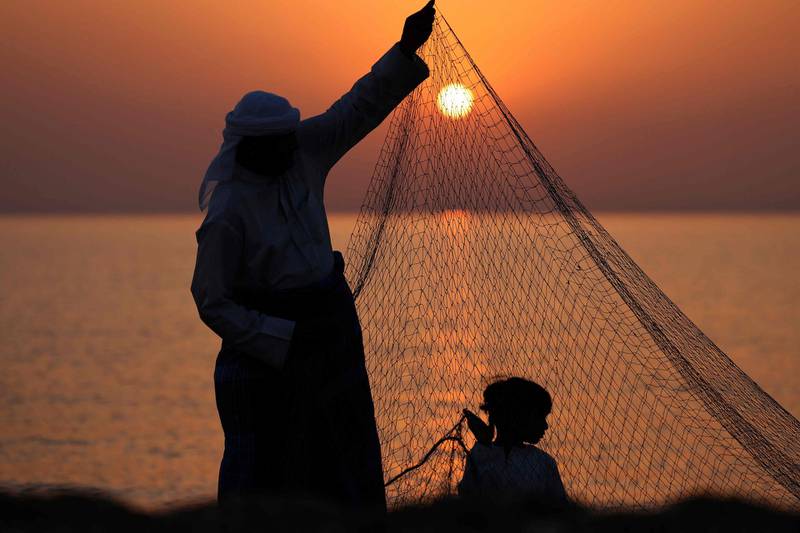 An Emirati fisherman helped by a child sets up nets on the shore of Dalma island in the Arabian Gulf, near Abu Dhabi. AFP