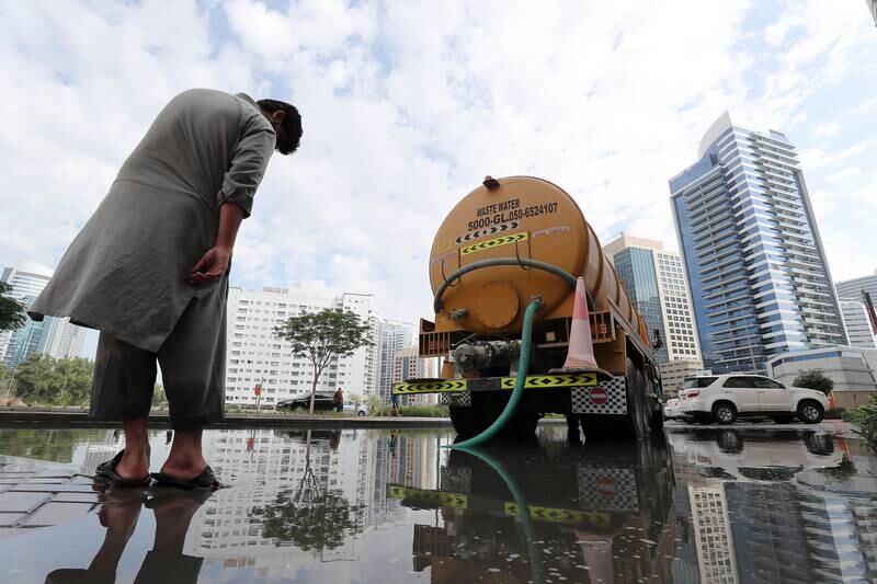 Workers clearing a flooded road after heavy rain in Al Barsha heights, Dubai. Pawan Singh / The National