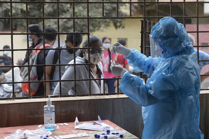 A health worker collects a swab sample from a woman to test for the coronavirus at a community hall in Hyderabad. AFP