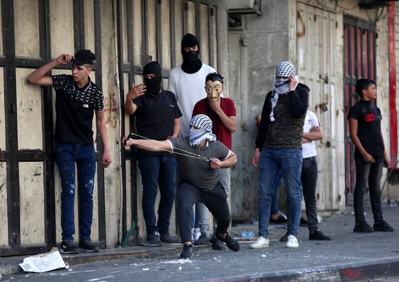 Palestinians throw stones at Israeli forces during protests over Jerusalem's annual flag march, in the West Bank city of Hebron. EPA