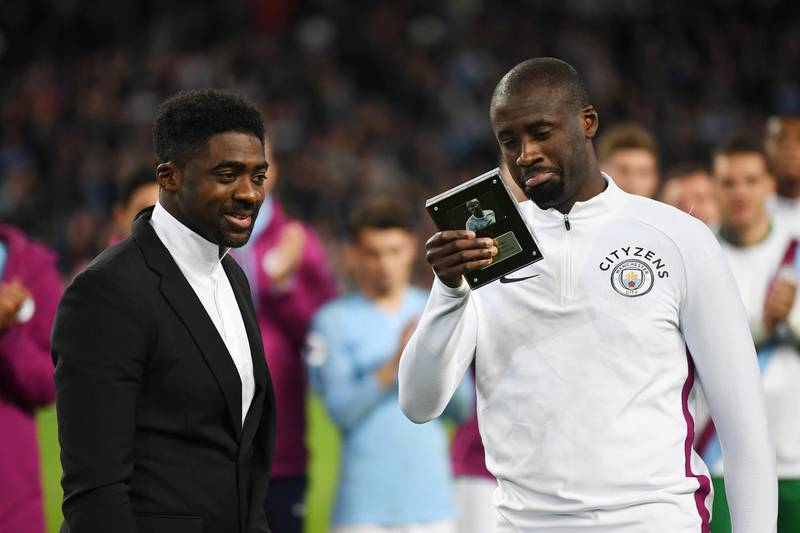 Manchester City's Yaya Toure looks at a gift as his brother Kolo Toure watches on. Gareth Copley / Getty Images