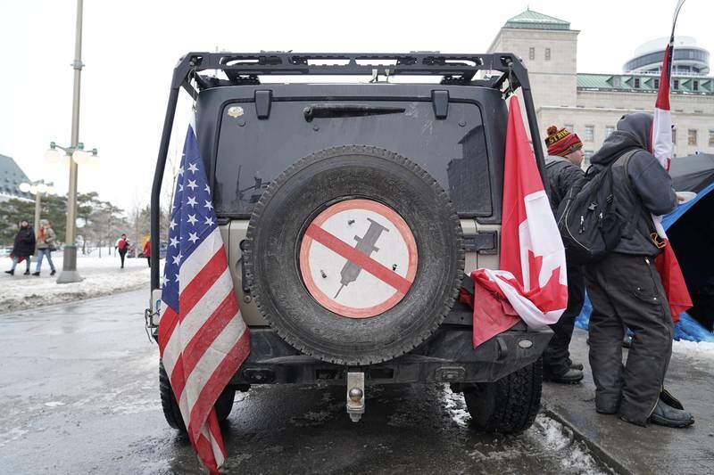 A car is decorated with an anti-vaccine sign and both the American and Canadian flags. Willy Lowry / The National