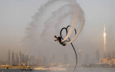 TOPSHOT - An athlete performs stunts with a water jet pack on the first day of the Dubai watersport festival, organised by the Dubai International Marine Club (DIMC), near the Burj Khalifa skyscraper in the Gulf emirate on June 25, 2020.  / AFP / KARIM SAHIB
