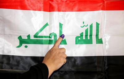 An Iraqi woman shows her ink-stained index finger before a national flag after having cast her vote in the parliamentary election, in the capital Baghdad's Karrada district. Sabah Arar / AFP