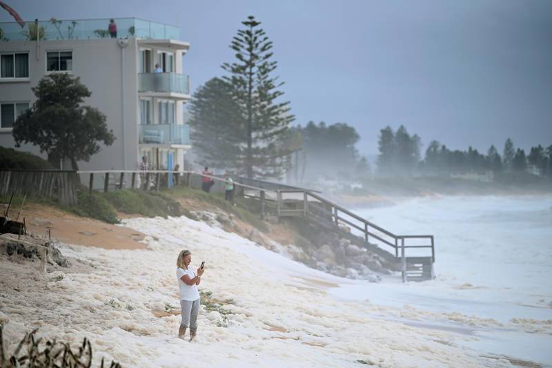 A resident inspects sea foam brought by waves approaching on beach front houses in Collaroy in Sydney's Northern Beaches. AAP Image via AP