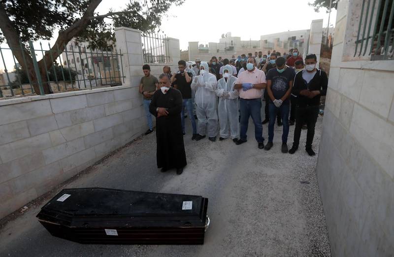Relatives pray next to a coffin with the body of 54-year-old Palestinian Mohammad Sallem, who died after contracting Covid-19, during his funeral in the West Bank city of Hebron.  EPA