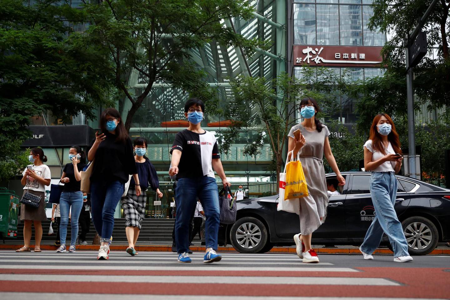 People wearing face masks leave an office building after work following a new outbreak of the coronavirus disease (COVID-19) in Beijing, China, June 29, 2020. REUTERS/Thomas Peter