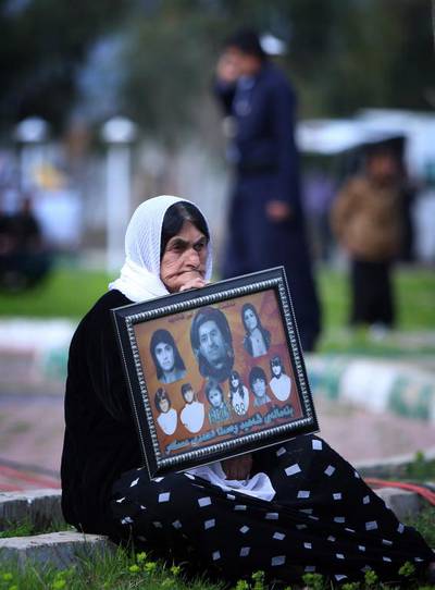 An Iraqi Kurd woman holds an image of loved ones as she visits in a grave yard for the victims of a gas attack.
