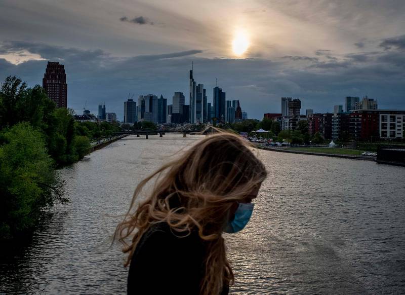 A woman wearing a face mask walks on a bridge over the river Main in Frankfurt, Germany. AP Photo