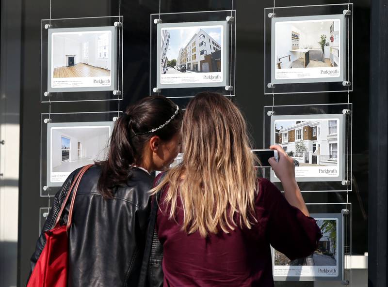 Les femmes étudient les prix des maisons dans la fenêtre d'un agent immobilier à Kentish Town, Londres.  Pennsylvanie