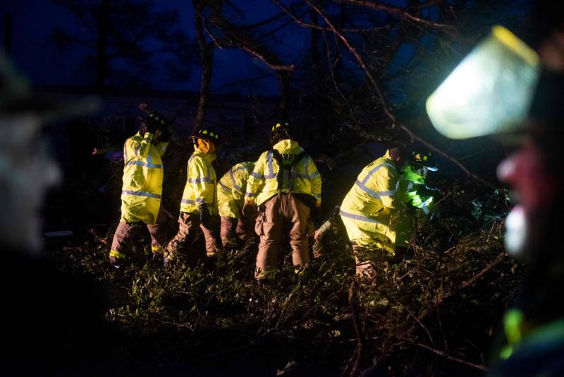 Firefighters cut through trees that fell on a road in Bourg. AFP