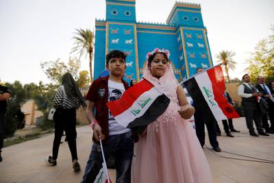 Children hold Iraqi flags during celebration after UNESCO designated ancient city of Babylon as World Heritage Site, in front of a replica of Ishtar gatee near Hilla, Iraq.  Reuters