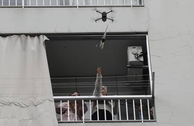 A woman on her balcony reaches out to catch a rose delivered to her via a drone on Mother's day, in the Lebanese coastal city of Jounieh, north of the capital Beirut  as people remain indoors in an effort to limit the spread of the novel coronavirus.  Three young Lebanese came up with the idea of delivering roses attached to drones, offered to mothers by their children as a surprise gift. The funds collected from this initiative will be donated to the Lebanese Red Cross to help fight against the CIVID-19 pandemic.  AFP