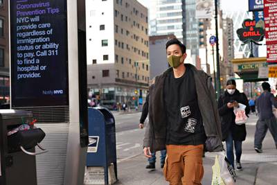 A man wearing a protective mask with a LinkNYC box displaying Coronavirus Prevention Tips in New York City. AFP