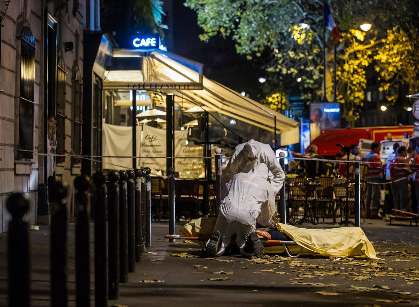 FILE - In this Friday, Nov. 13, 2015 file photo, investigating police officers inspect the lifeless body of a victim of a shooting attack outside the Bataclan concert hall in Paris. French judges investigating the 2015 Islamic State attacks that left 130 people dead in Paris have ordered charges against 20 people on Monday, including a Belgian accused of masterminding the attacks who was held for years in Abu Ghraib prison in Iraq before being freed and returned home. (AP Photo/Kamil Zihnioglu, File)