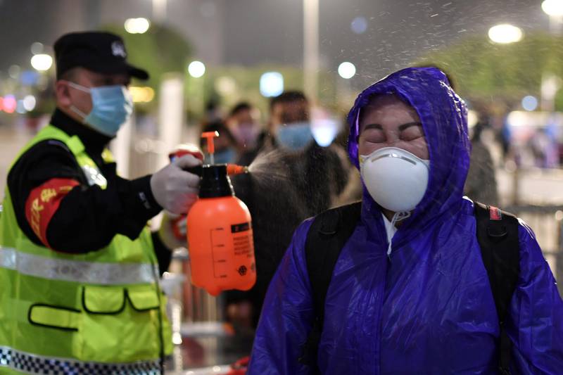 A police officer sprays disinfectant on a traveller outside Hankou Railway Station after travel restrictions to leave Wuhan were lifted. Reuters