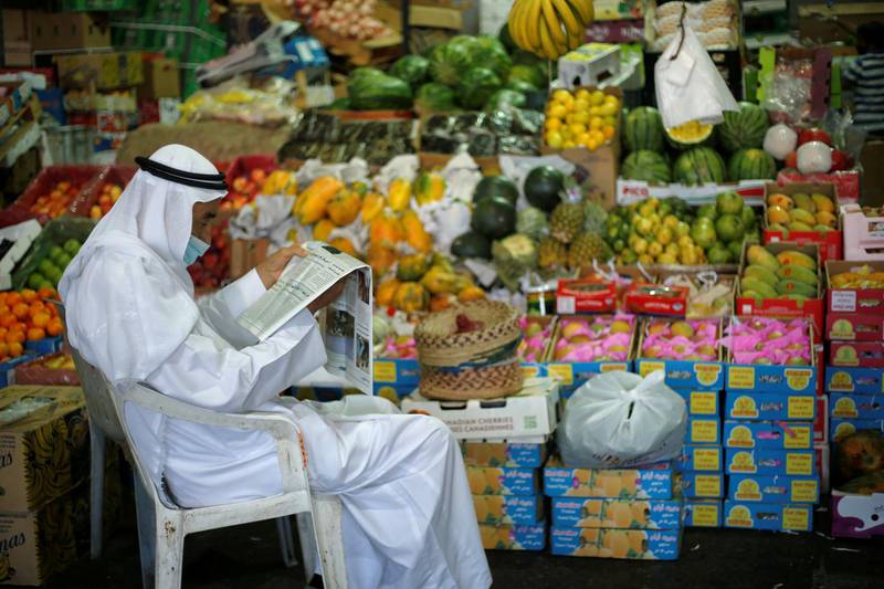 A Bahraini vendor, wearing a face mask, following the outbreak of the coronavirus disease (COVID-19), reads a newspaper as he waits for customers at his fruits stand, in Central Market, in Manama, Bahrain. REUTERS