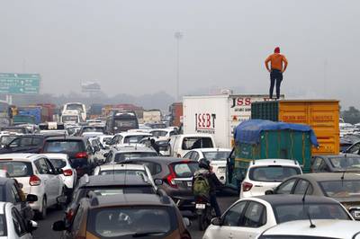 In this photo taken on December 19, 2019 a man stands on a truck to look at a huge traffic jam on the highway towards New Delhi on the outskirts of Gurgaon, as police set up roadblocks on the Haryana state border amid demonstrations against India's new citizenship law. Indians defied bans on assembly on December 19 in cities nationwide as anger swells against a citizenship law seen as discriminatory against Muslims, following days of protests, clashes and riots that have left six dead. AFP