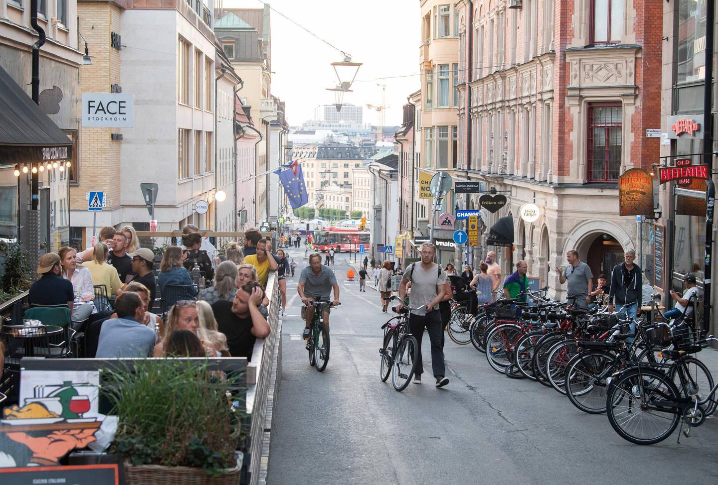 People with bicycles pass an outdoor restaurant on a street in the Sodermalm neighbourhood of Stockholm, Thursday, August 20, 2020. (Fredrik Sandberg/TT News Agency via AP)