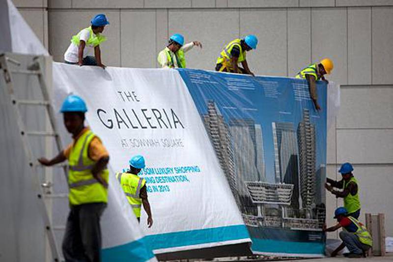 United Arab Emirates, Abu Dhabi, April 19, 2012:   Work and clean-up on Sowwah Square and surrounding construction sites continues at a steady pace on Monday, Apr. 23, 2012, at the Sowwah Island in Abu Dhabi. Here, workers hand a banner for the new Galleria Mall. The island has been renamed Marjan Island. (Silvia Razgova / The National)