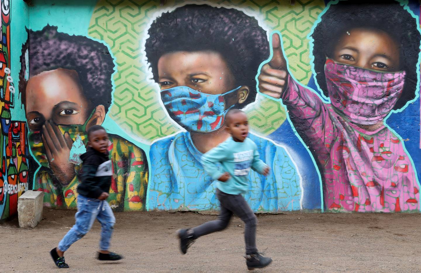 Boys pass a mural of children wearing facemasks amid the coronavirus disease outbreak, at Soweto's Kliptown, South Africa, October 27, 2021.  Reuters 
