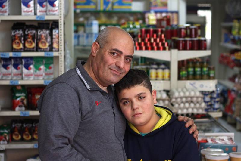 Syrian refugees Omar Al Naji and his son Abdullah, 10, in the minimarket they work at in the town of Khalde, south of Beirut. Abdullah wants to be a doctor or engineer when he grows up, but he cannot read or write and has never been to school. Mr Naji hopes to escape with his family to Europe when winter ends. Josh Wood for The National
