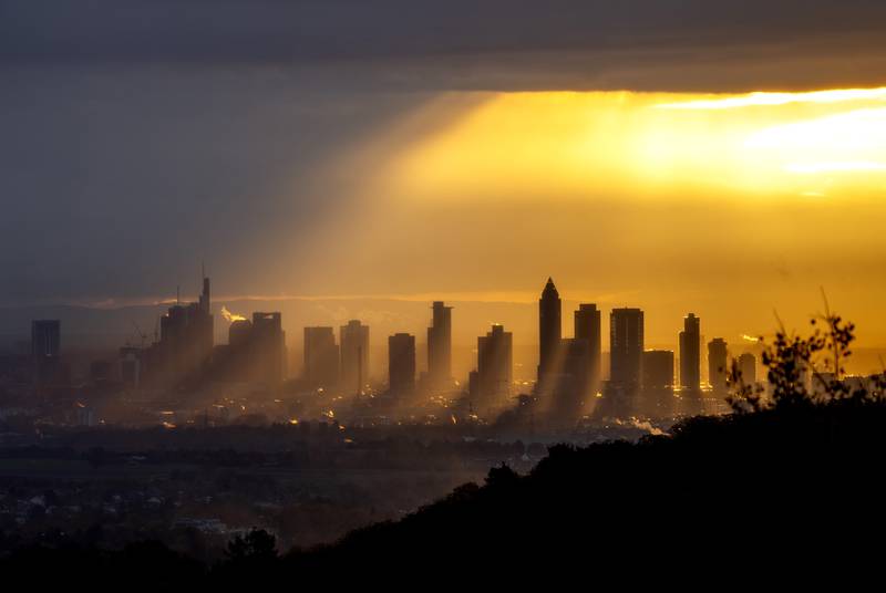 Sunrays shine through the clouds over buildings in the central banking district of Frankfurt, Germany. AP