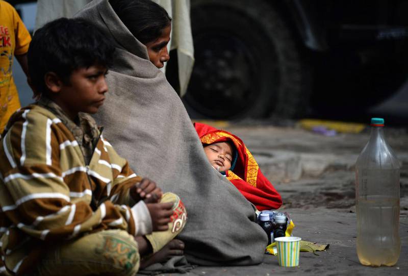 An Indian woman sits with her children on a foot path in New Delhi. Sajjad Hussain / AFP Photo