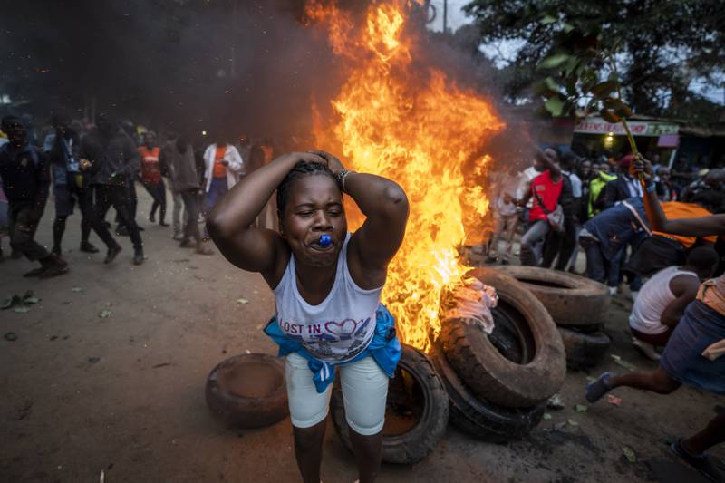 A supporter of defeated presidential candidate Raila Odinga protests next to a roadblock of burning tyres in Kibera. AP Photo