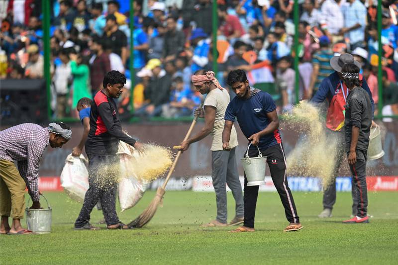 Ground staff use saw dust to dry the playing field following rain on Tuesday. FP