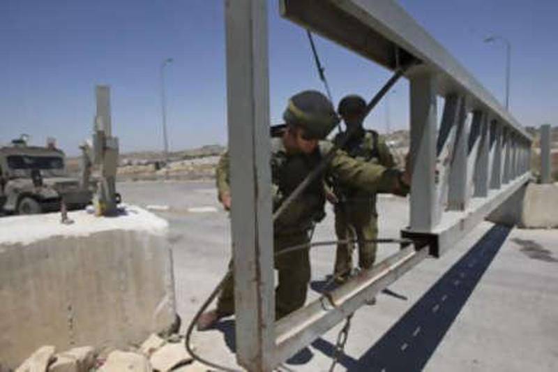 An Israeli soldier opens a gate at a checkpoint between the West Bank city of Hebron and a commercial crossing point into Israel on August 7, 2008.